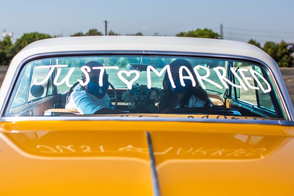 Philip Hernandez (L) and Marcela Peru pose for a picture inside their car at the Honda Center parking lot after they were married by a county clerk on April 21, 2020 in Anaheim , California. - Sputnik Azərbaycan