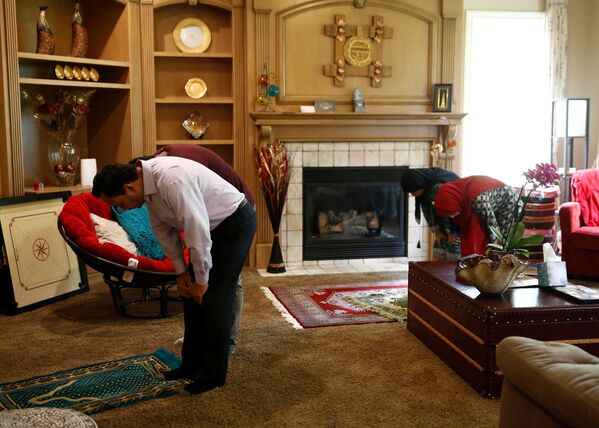 Hyder Ali, the president of the Muslim Association of Puget Sound, prays at home with son Zayaan - Sputnik Azərbaycan