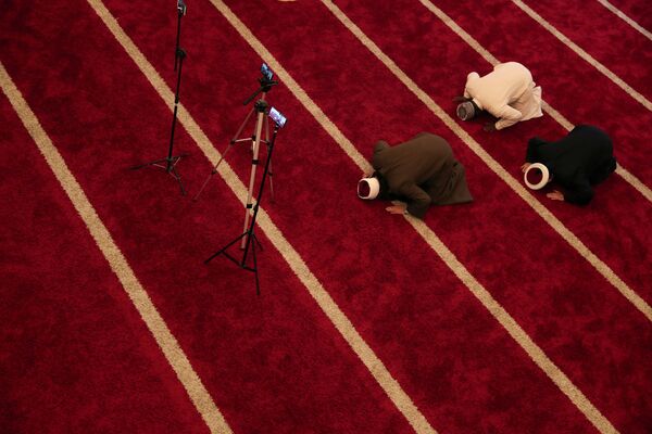 Sheikh Mohamad Al Bukai together with Sheikhs Muhammad Alla Eldine and Caido Bashir Mudera from other mosques conduct a social media live stream of the Taraweeh prayer in an almost empty mosque - Sputnik Azərbaycan