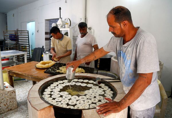 Workers prepare traditional sweets for sell during the holy fasting month of Ramadan, amid the spread of the coronavirus disease (COVID-19), at a shop in Najaf, Iraq, April 26, 2020. - Sputnik Azərbaycan