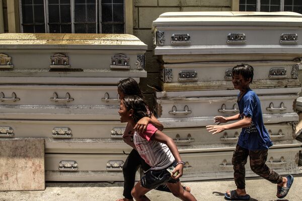 Дети во время игры у гробов в крематории в Маниле - Sputnik Азербайджан