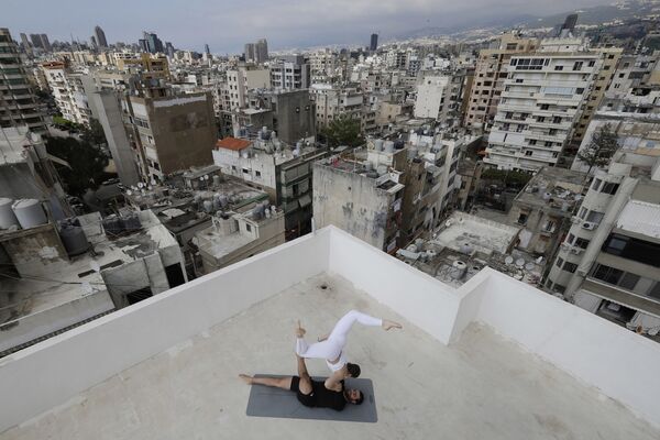 Инструктора занимаются йогой на крыше многоквартирного дома в бейрутском районе Айн-эль-Ремманех - Sputnik Азербайджан