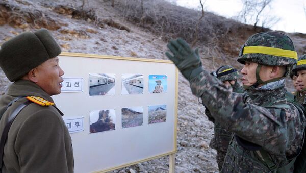 Южнокорейский солдат (справа), разговаривающий с северокорейским солдатом (слева) во время проверки демонтированного северокорейского сторожевого поста - Sputnik Azərbaycan