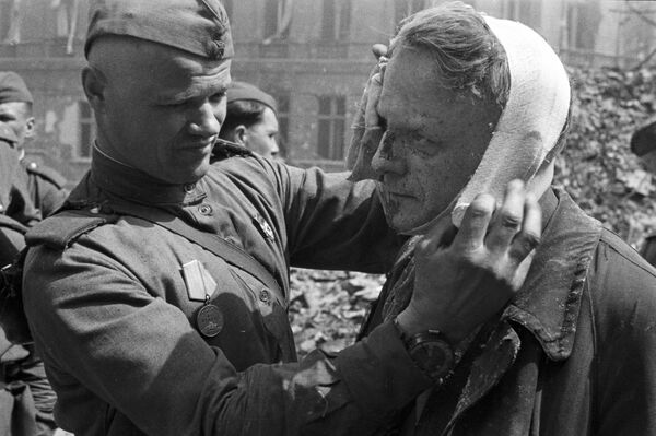 Советский солдат делает перевязку раненому берлинцу, 1945 год - Sputnik Азербайджан