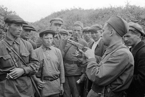 Командир партизанского отряда знакомит бойцов с оружием. Смоленская область, 1941 год - Sputnik Азербайджан