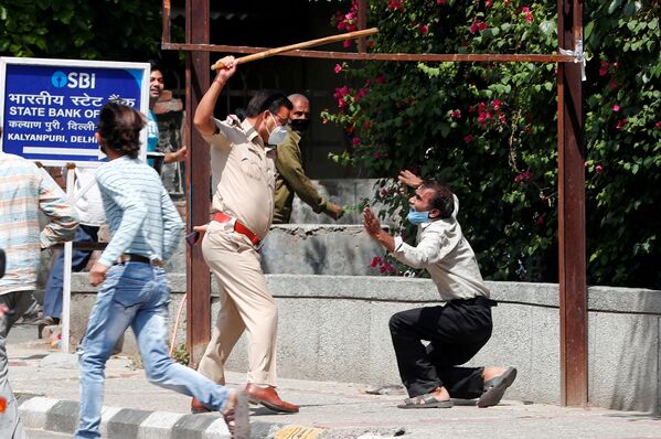 Офицер полиции с дубинкой с нарушителем карантина в Нью-Дели, Индия - Sputnik Азербайджан