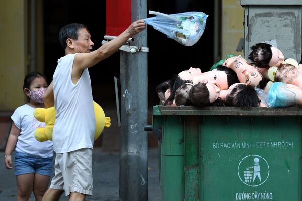 Мужчина бросает мусор в мусорный бак с головами манекенов в Ханое, Вьетнам - Sputnik Азербайджан