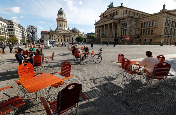 Люди наслаждаются погодой в кафе на площади Жандарменмаркт в Берлине, соблюдая принцип социальной дистанции - Sputnik Азербайджан