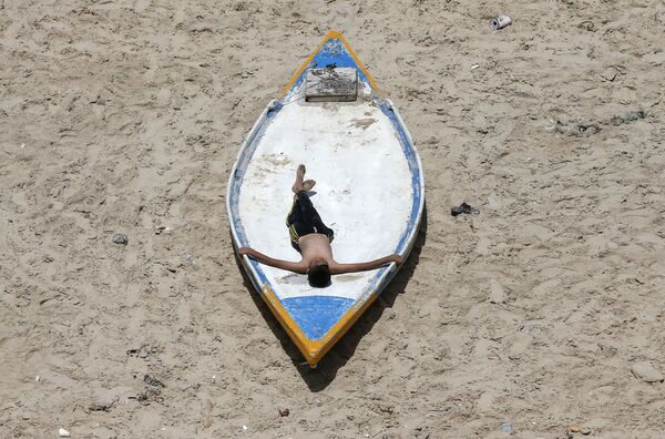 Палестинский юноша во время отдыха на пляже в Газе  - Sputnik Азербайджан