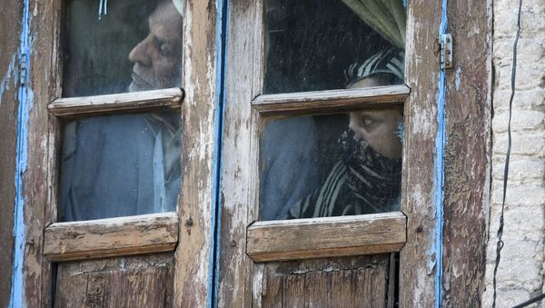 Люди смотрят из окна своего дома в Сринагаре, Индия - Sputnik Azərbaycan