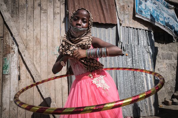 Девочка-сирота с новым обручем во время раздачи еды и игрушек детям-сиротам в 11-ти детских домах в связи с праздником Ураза-байрам в Кении - Sputnik Азербайджан