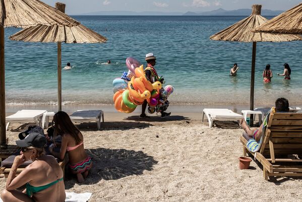 Отдыхающие и продавец игрушек на городском пляже Алимос в пригороде Афин - Sputnik Azərbaycan