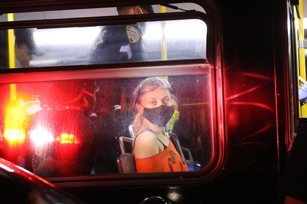 Протестующая в маске после задержания в полицейском автобусе у Барклайс-Центр в Бруклине, США - Sputnik Азербайджан
