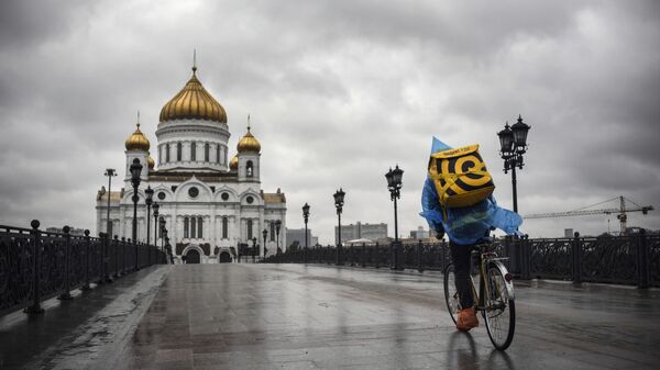 Курьер, доставляющий еду, на велосипеде у Храма  Христа Спасителя в центре Москвы - Sputnik Азербайджан
