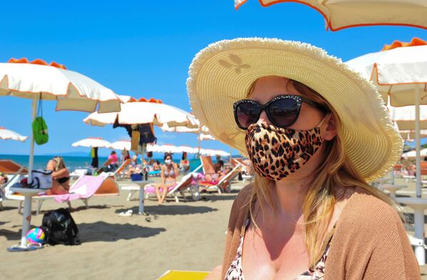 Женщина в защитной маске и солнцезащитных очках на пляже в Кастильоне-делла-Пеская, Италия - Sputnik Azərbaycan