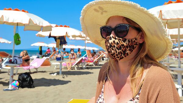 Женщина в защитной маске и солнцезащитных очках на пляже в Кастильоне-делла-Пеская, Италия - Sputnik Azərbaycan