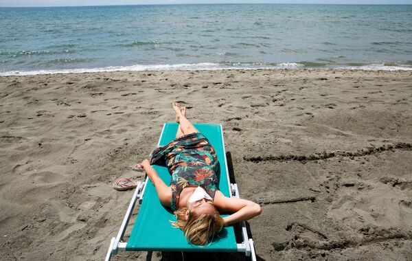 Девушка загорает на пляже в Италии - Sputnik Азербайджан