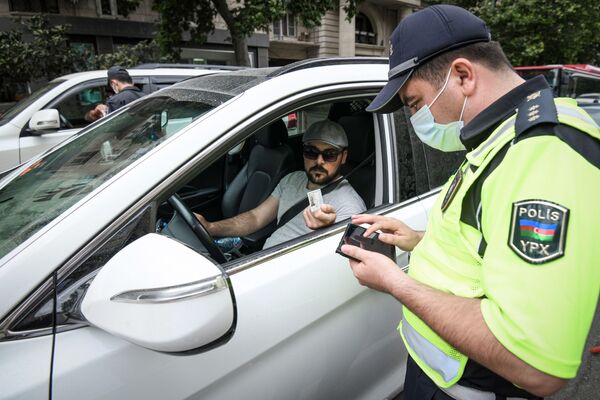 Сотрудник дорожной полиции проверяет разрешение водителя для выходы на улицу - Sputnik Azərbaycan