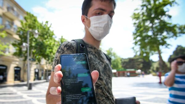 Молодой человек показывает смс-разрешение для выхода на улицу - Sputnik Азербайджан