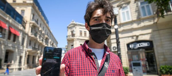 Молодой человек показывает смс-разрешение для выхода на улицу Молодой человек показывает смс-разрешение для выхода на улицу - Sputnik Азербайджан