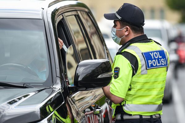 Сотрудник дорожной полиции проверяет разрешение водителя для выходы на улицу - Sputnik Azərbaycan