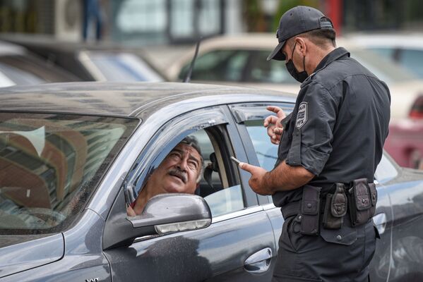 Сотрудник полиции проверяет разрешение водителя для выходы на улицу - Sputnik Azərbaycan