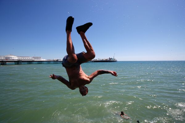 Мужчина прыгает в воду на пляже в Брайтоне, Великобритания - Sputnik Азербайджан