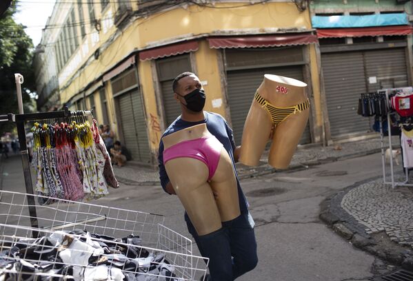 Продавец в защитной маске переносит манекены на уличном рынке в Рио-де-Жанейро - Sputnik Азербайджан